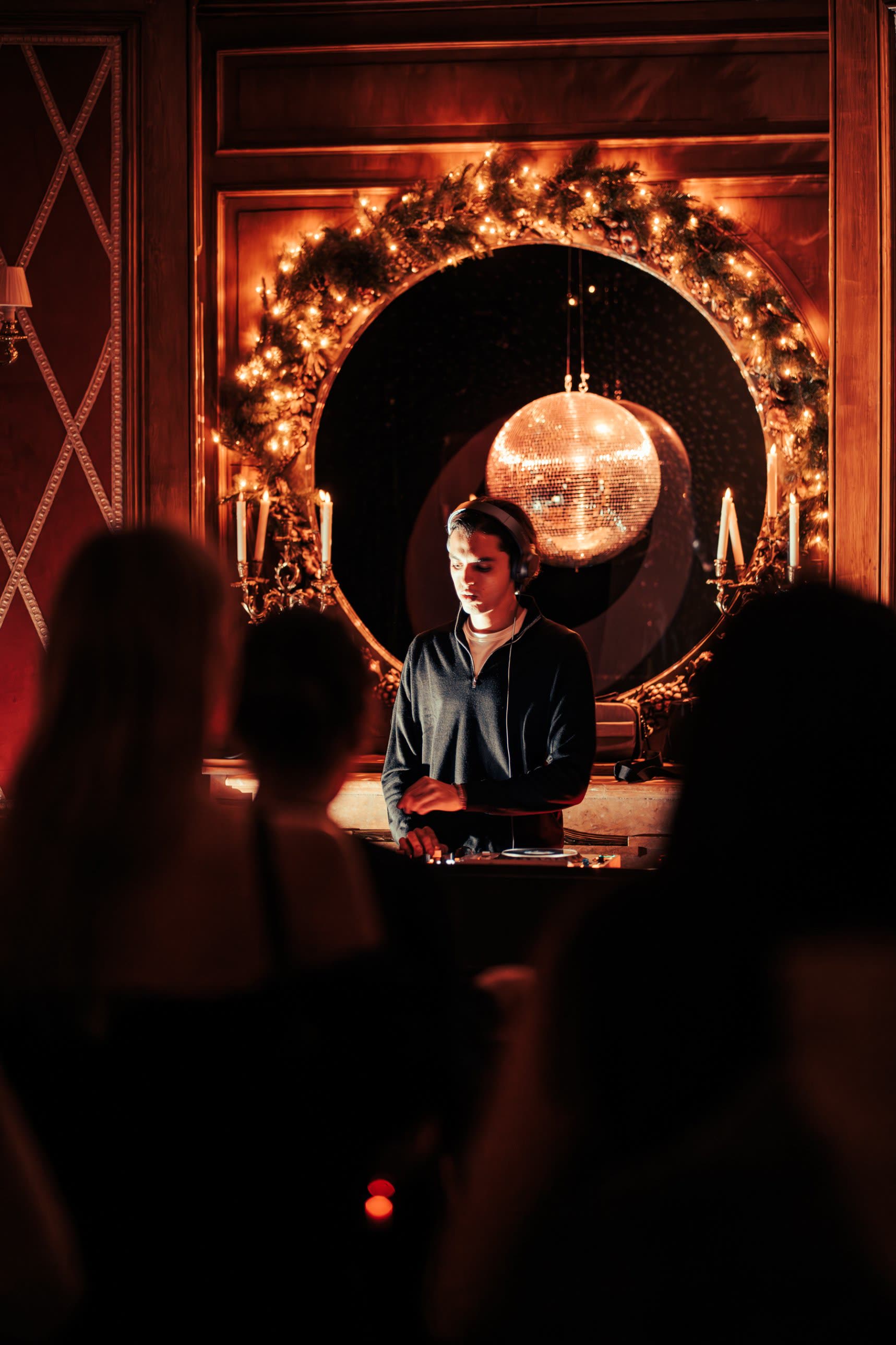 ARGANA at the decks in front of a round mirror framed with lights